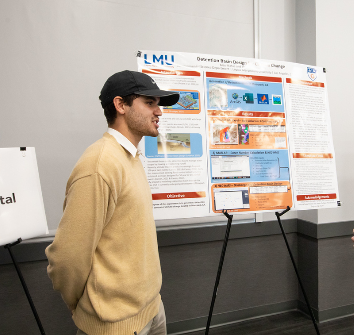 Student in a cap presenting a research poster